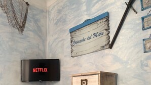 A room with a wooden cabinet, a wall-mounted TV, and a decorative sign. - The Sea Flower (Sanremo)