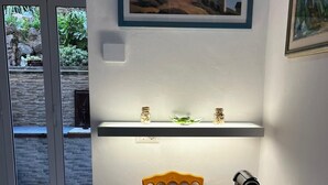 A dining area with a table set for two, a painting of a lighthouse, and a view through a glass door. - The Sea Flower (Sanremo)