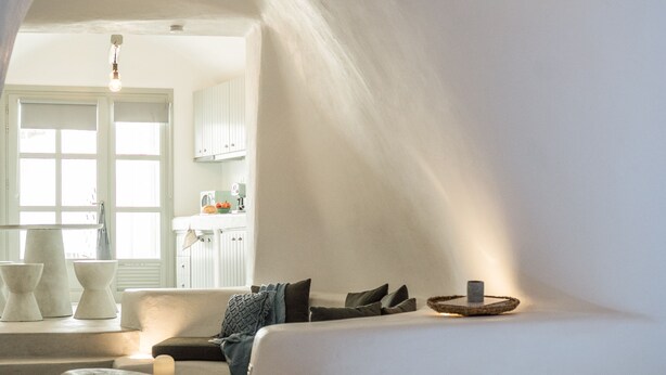 Un dormitorio acogedor con una cama grande, una pequeña zona de estar y vistas a una cocina y comedor a través de un arco.