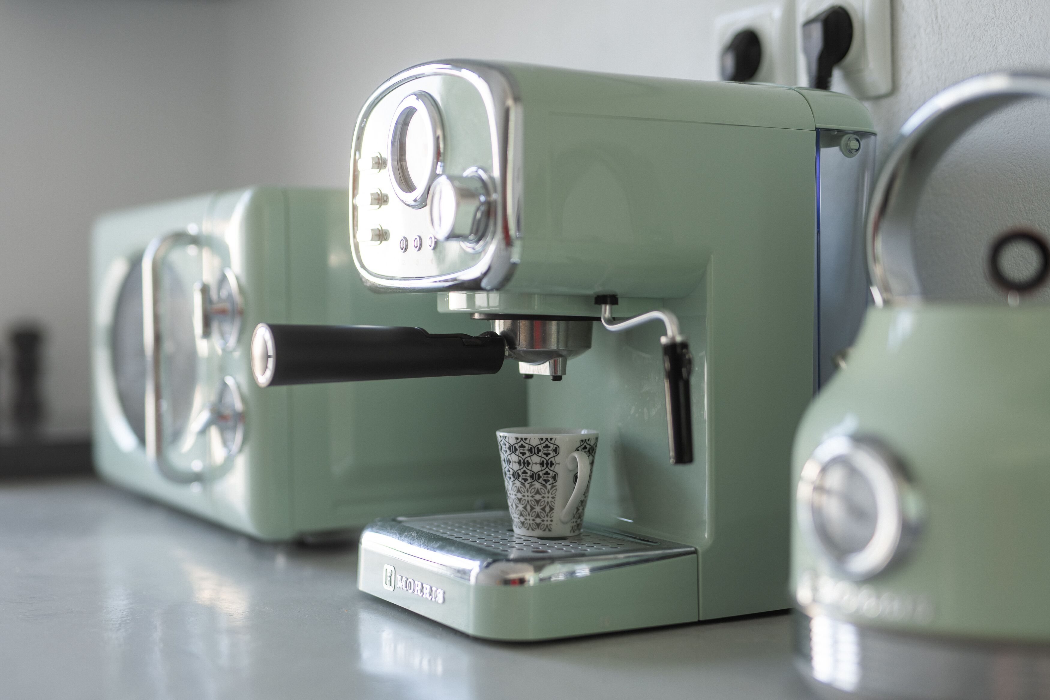 A vintage-style espresso machine with a cup placed on its drip tray.
