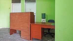 Une pièce avec un bureau en bois, une porte blanche et un mur vert.