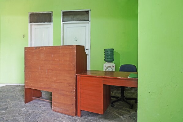 Um quarto com uma escrivaninha de madeira, uma porta branca e uma parede verde.