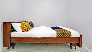 Un lit simple avec un cadre en bois, une literie blanche et des coussins à motifs.
