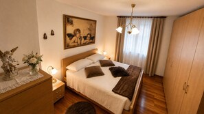 A bedroom with a bed, bedside tables, a dresser, a painting, and a wardrobe.
