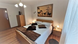 A bedroom with a bed, bedside tables, a nightstand, a wardrobe, a painting, and a chandelier. - LE RONDINI 3 rooms Wi-Fi sun nature pet friendly panoramic veranda (Montagnaga di Pinè)