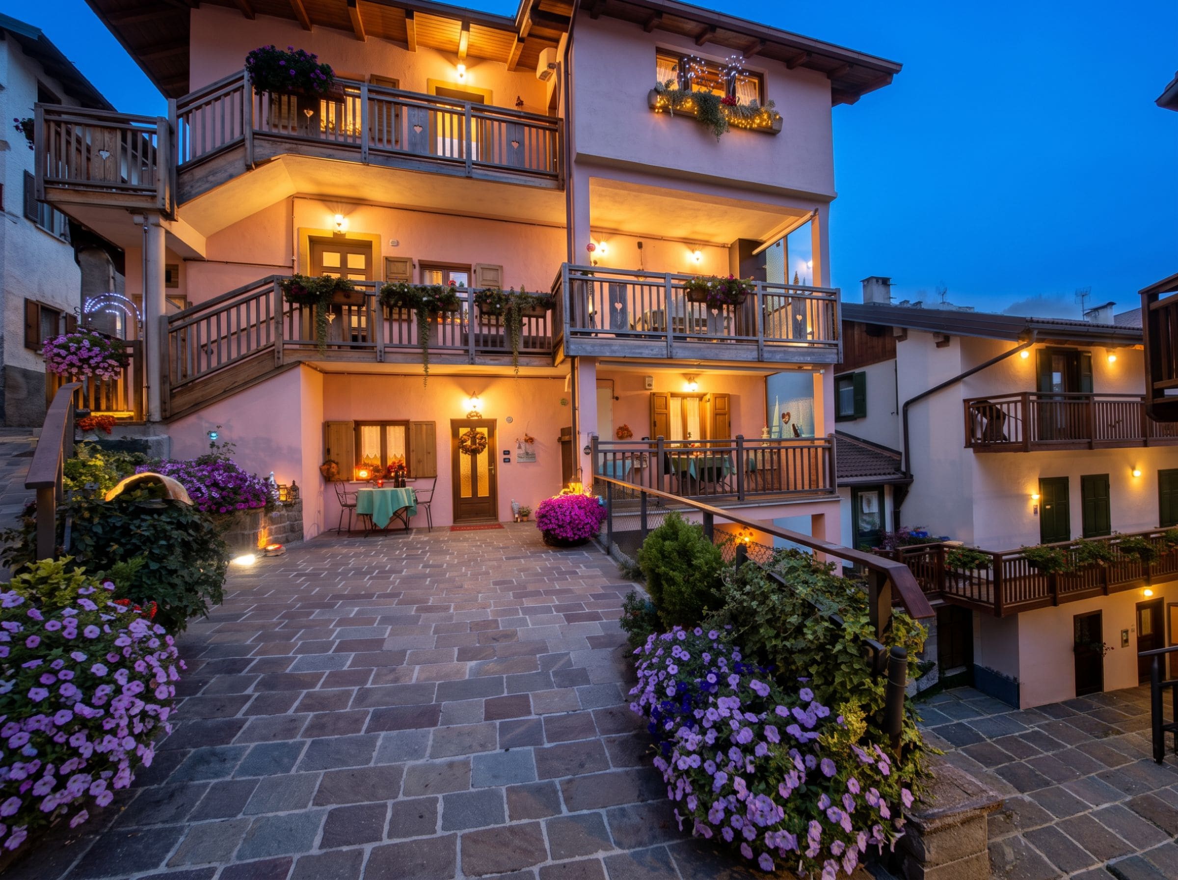 A multi-story hotel with balconies, a stone-paved courtyard, and flower arrangements.