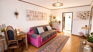 A cozy living room with a pink sofa, a wooden desk, and a patterned rug.
