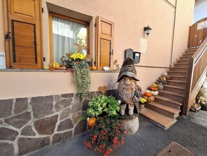 A stone wall, wooden shutters, a gnome statue, and a staircase.