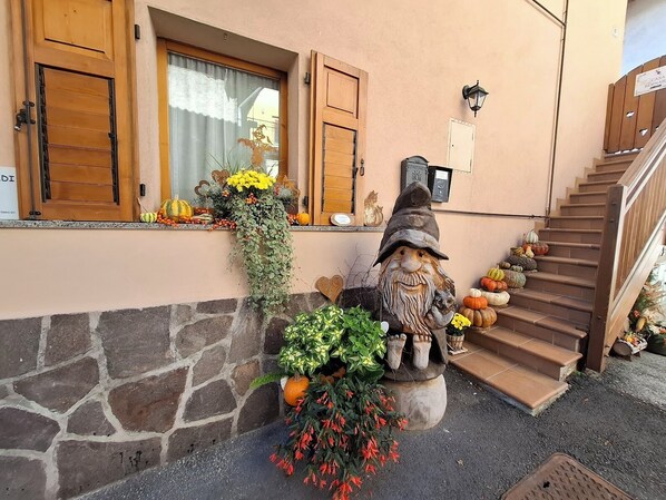 A stone wall, wooden shutters, a gnome statue, and a staircase.