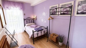 A bedroom with a bed, a hanging chair, a radiator, a window with curtains, and wall decorations.