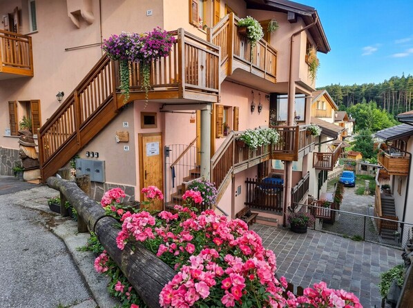A multi-story building with wooden balconies, flower boxes, and a stone facade.
