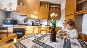A kitchen with wooden cabinets, a microwave, a stove, and a table with a patterned tablecloth.