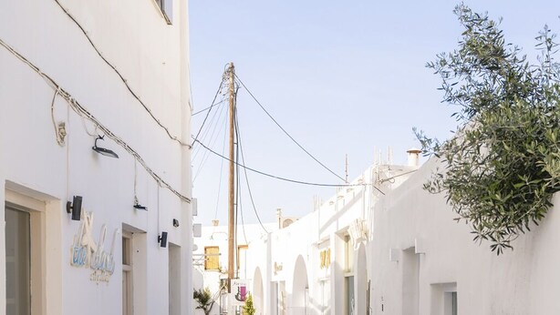 A narrow, cobblestone street flanked by white buildings with arched doorways and small windows. - Afluencia Complex Studio 6 by Mykonianvilla (Naousa)