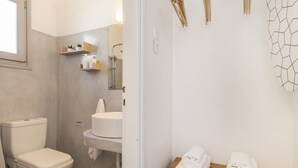A bathroom with a toilet, sink, and shower. There are towels on a wooden table. - Afluencia Complex Studio 6 by Mykonianvilla (Naousa)