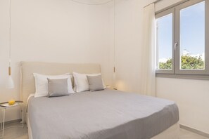 A bedroom with a bed, pillows, a nightstand, a lamp, and a window with a view. - Afluencia Complex Studio 6 by Mykonianvilla (Naousa)