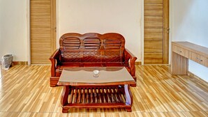 A room with a wooden floor, a wooden sofa with a glass table, and two wooden doors. - OYO Life 91989 K24 Residence Syariah (Palembang)