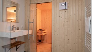 A modern bathroom with a wooden interior, a glass shower enclosure, and a white sink with a mirror. - Vloedschuur Generation home (Nieuwvliet-Bad)