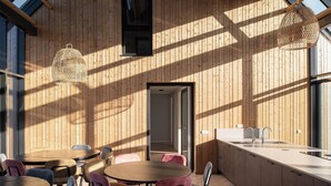A modern interior with wooden panel walls, a round dining table, and hanging light fixtures. - Vloedschuur Generation home (Nieuwvliet-Bad)