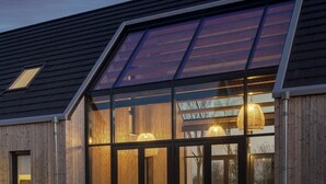 A modern building with a sloped roof, large windows, and wooden paneling. - Vloedschuur Generation home (Nieuwvliet-Bad)