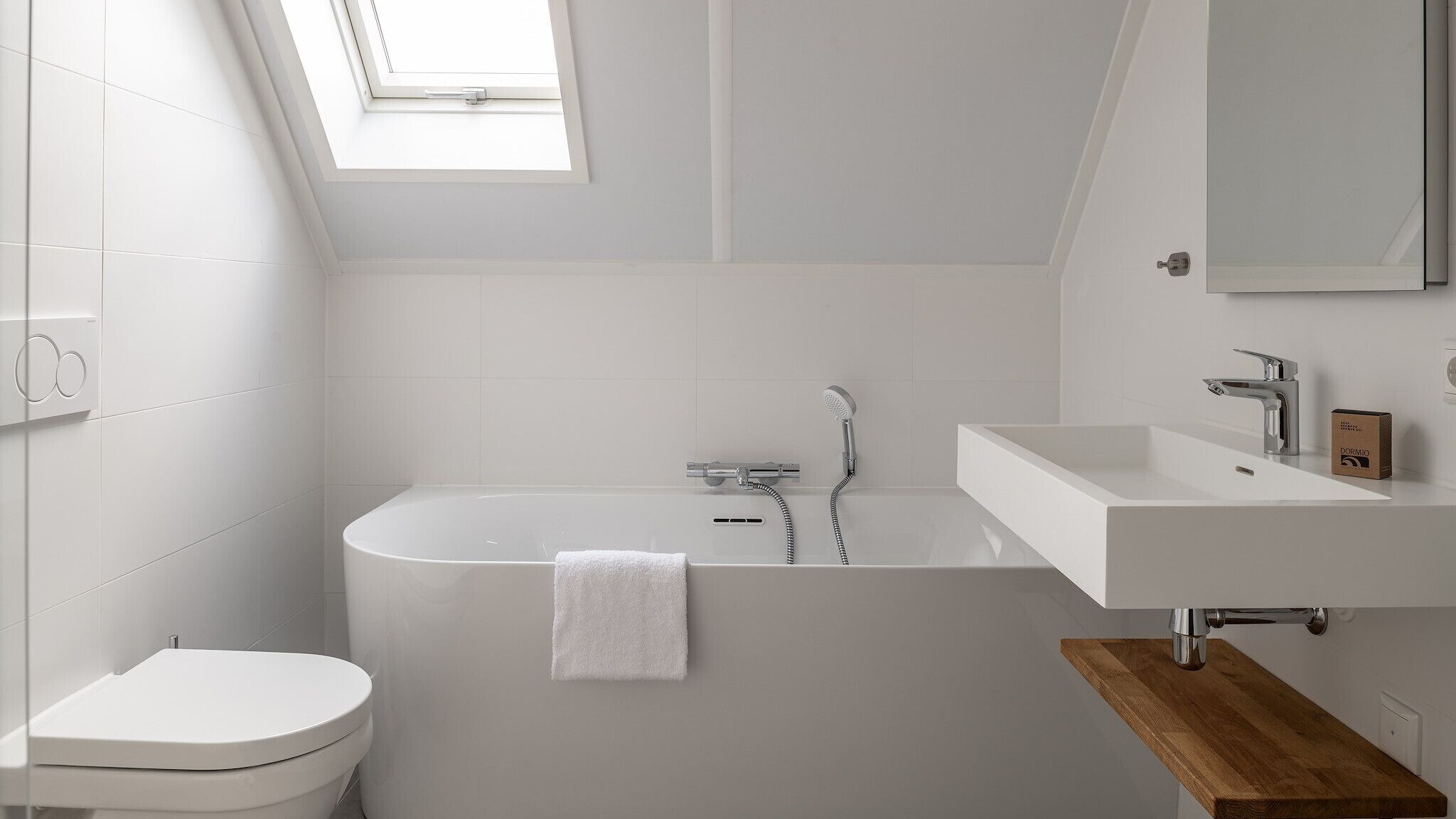 A modern bathroom with a freestanding bathtub, a toilet, and a vanity with a mirror.