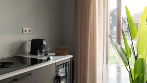 Een keuken met een koffiezetapparaat, twee glazen en een doos op het aanrecht.