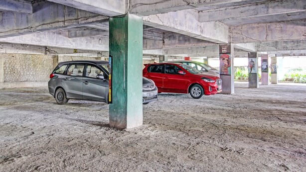 A parking garage with concrete pillars and a sandy floor.