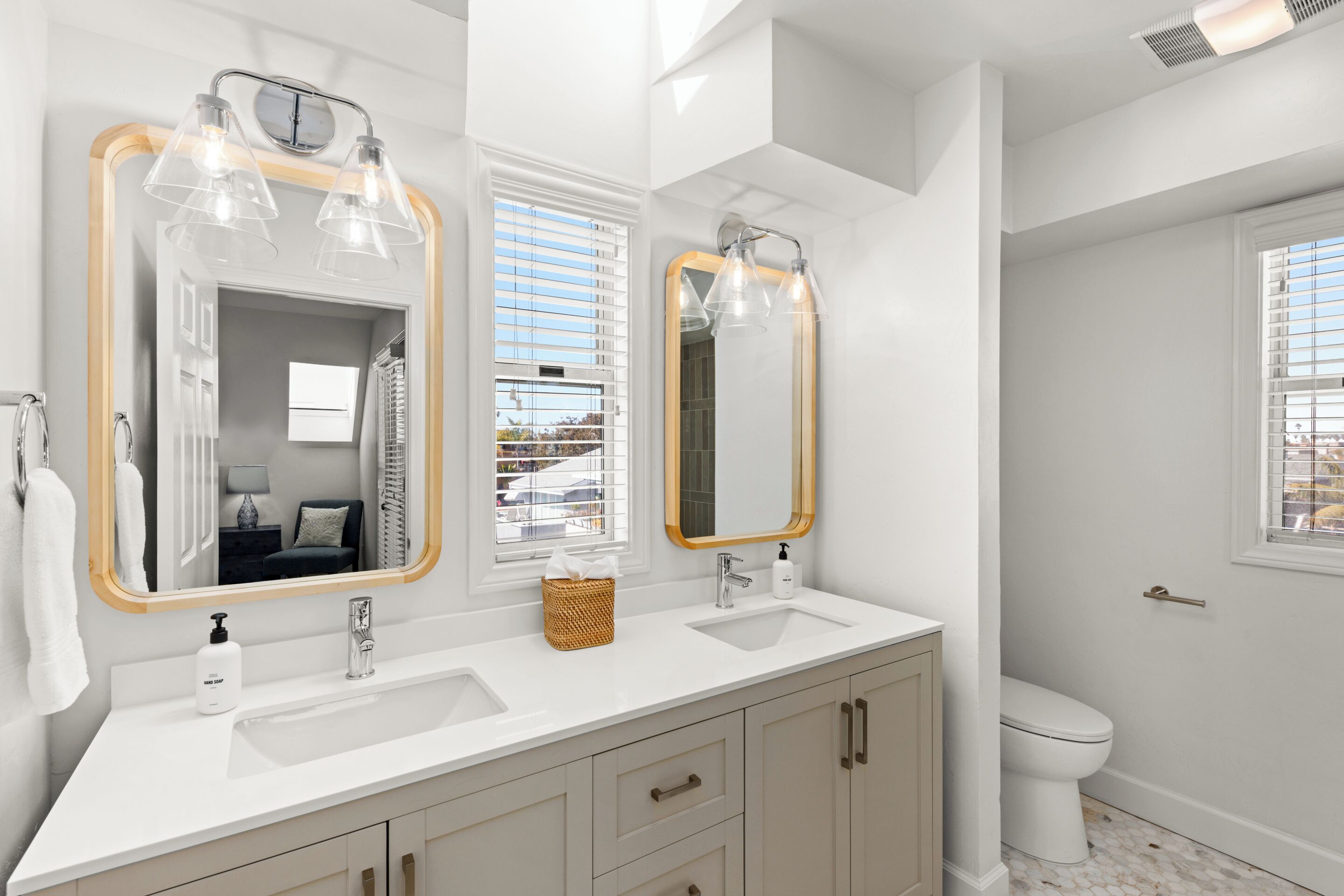 Une salle de bain moderne avec deux lavabos, un grand miroir et des toilettes.