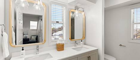 Une salle de bain moderne avec deux lavabos, un grand miroir et des toilettes.