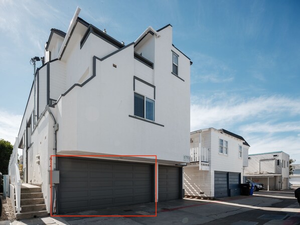 Un immeuble résidentiel moderne à deux étages, doté d’un garage, d’une petite fenêtre et du numéro « 710 » bien visible sur la porte du garage.