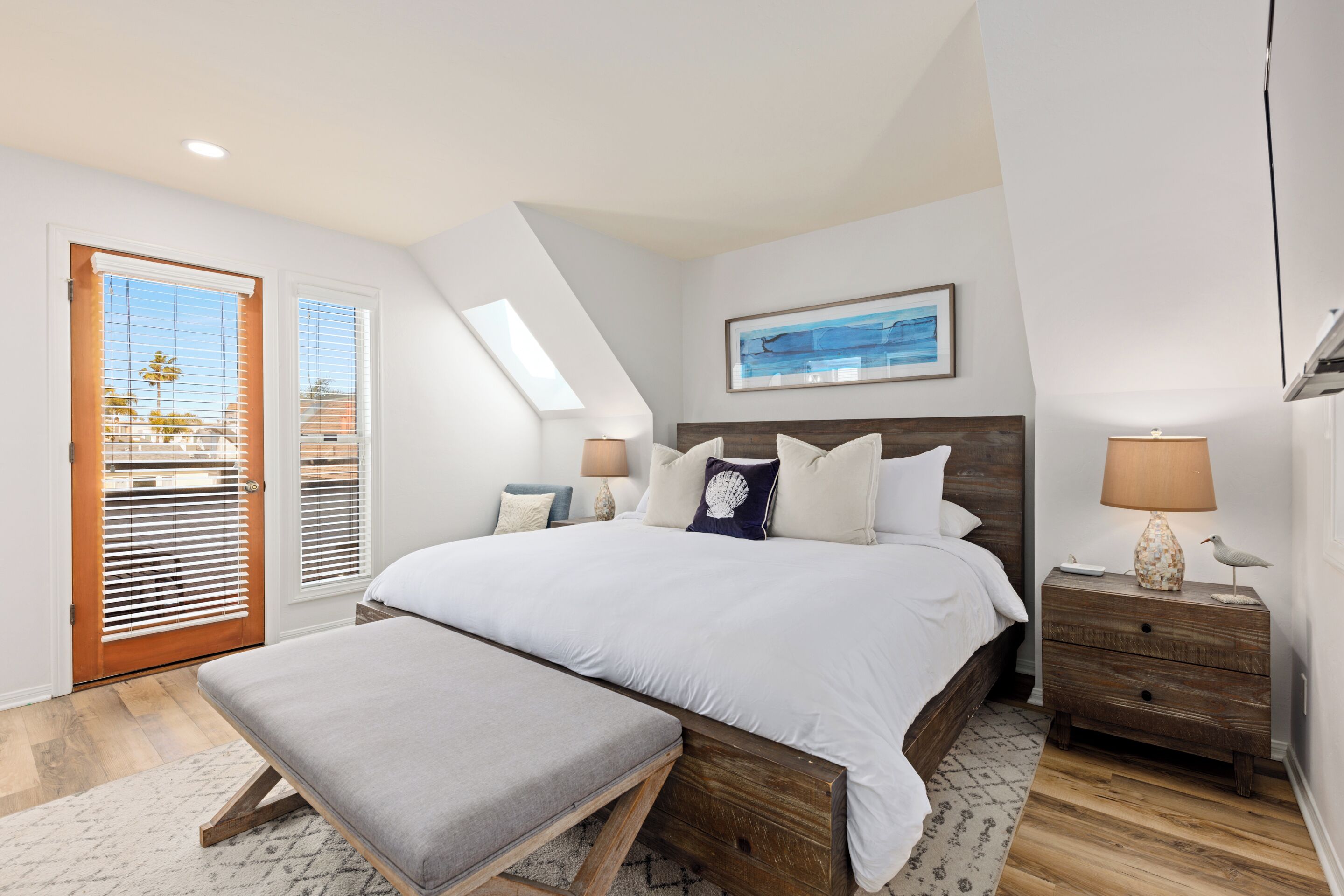 Ein Schlafzimmer mit einem großen Bett, einer Bank, einem Nachttisch und einem Fenster mit Jalousien.