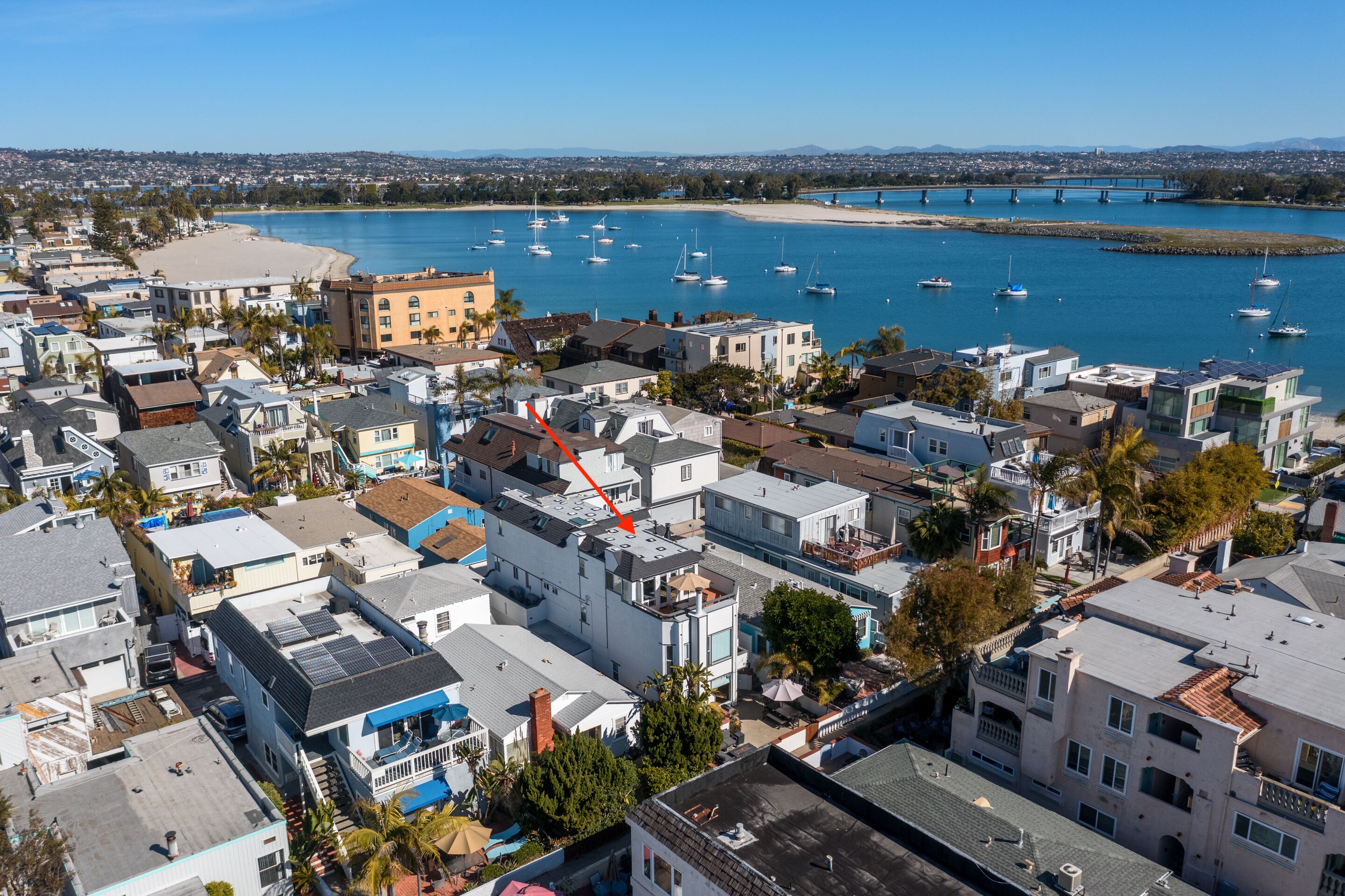A coastal town with a marina, residential buildings, and a bridge in the background.