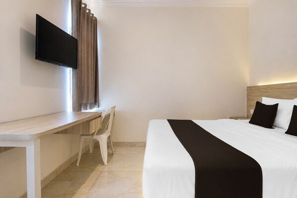 A hotel room with a bed, a desk, a chair, a flat-screen TV, and a window with curtains. - Collection O near Ambarrukmo Plaza Mall formerly Damar Kusumo Guest House (Depok)
