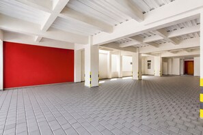 A spacious interior with a red wall, tiled flooring, and white structural beams. - Collection O near Ambarrukmo Plaza Mall formerly Damar Kusumo Guest House (Depok)