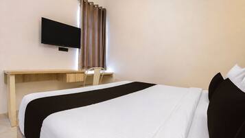 A hotel room with a bed, a desk, a chair, and a television mounted on the wall.