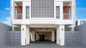 A modern building with a central entrance, two balconies, and a patterned facade. - Collection O near Ambarrukmo Plaza Mall formerly Damar Kusumo Guest House (Depok)