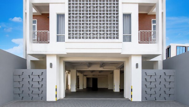 Un edificio moderno con entrada central, dos balcones y fachada con diseño.