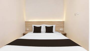 A narrow hotel room with a single bed, two bedside tables, and a wooden headboard.