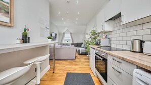 A modern kitchen with white cabinets, a black countertop, and a built-in oven. A gray rug is on the floor, and a plant is on the countertop. - Dunluce Park - Portrush by the Sea (Portrush)