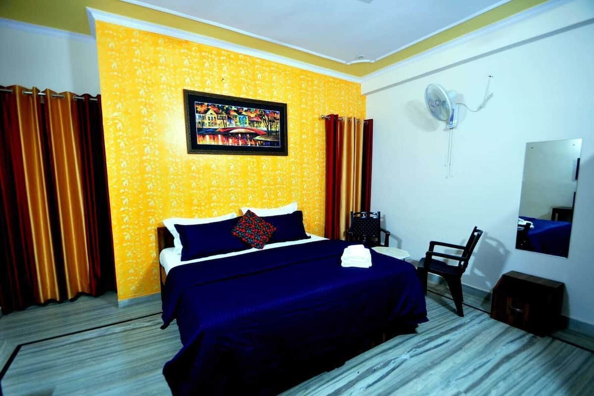 Una habitación de hotel con una cama, una silla, un ventilador y un cuadro en la pared.