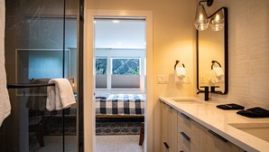 Un baño moderno con un espejo grande, dos lámparas de luz y una ventana visible.