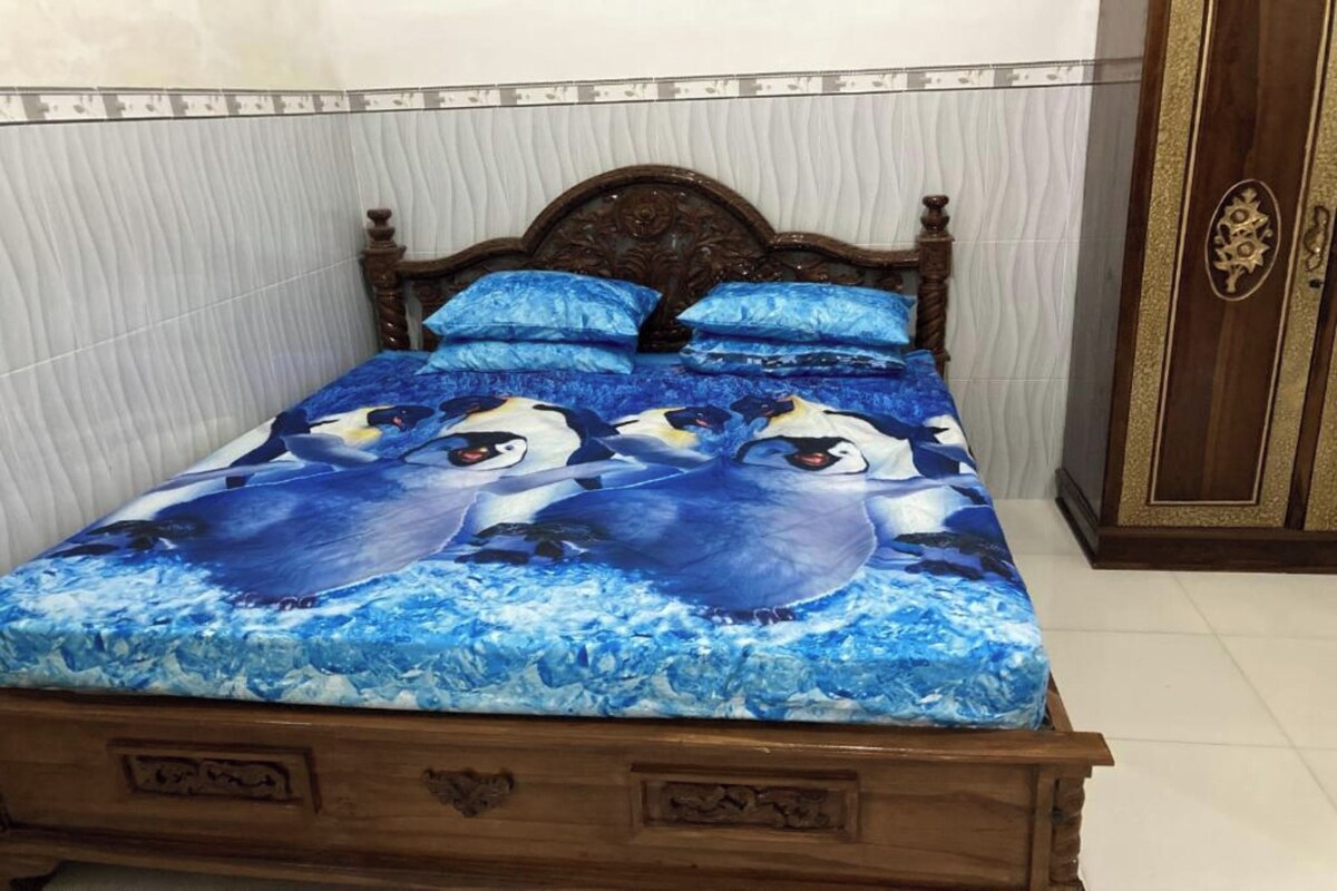 Una cama con colcha de diseño azul y blanco, cabecera de madera y armario con pomo decorativo.