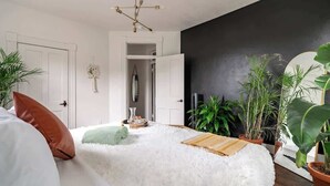 A bedroom with a fluffy white bed, a wooden side table, and a black accent wall. - Downtown Chillicothe | Walk to Historic District | Free Parking | 5,800+ Reviews (Chillicothe)
