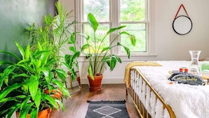 A bedroom with a bed, a window, and several potted plants. - Downtown Chillicothe | Walk to Historic District | Free Parking | 5,800+ Reviews (Chillicothe)
