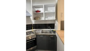 A compact kitchen with a stove, sink, and black cabinets. - Sweet Appart Centre Urbain Nord Aéroport Annul Flex (Tunis)