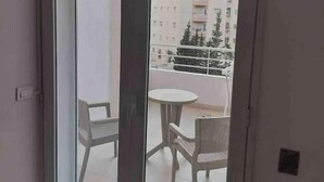 A balcony with a glass door, a small table, and two chairs. - Sweet Appart Centre Urbain Nord Aéroport Annul Flex (Tunis)