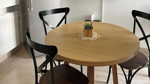 A compact kitchen with a refrigerator, a flat-screen TV mounted on the wall, and a round wooden dining table surrounded by chairs. - Sweet Appart Centre Urbain Nord Aéroport Annul Flex (Tunis)