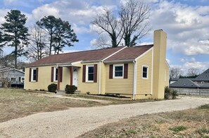 A single-story house with a chimney, a front porch, and a driveway. - Vibrant 3BR Ranch | Prime Greensboro Location (Greensboro)