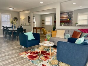 A modern living room with a sofa, two armchairs, a coffee table, and a dining area with chairs and a table. - Vibrant 3BR Ranch | Prime Greensboro Location (Greensboro)