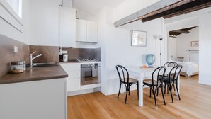 Een moderne keuken met witte kasten, een houten aanrecht en een eethoek met een tafel en stoelen.