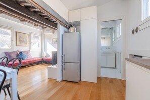 A compact living space with a kitchenette, a dining area, and a seating area with a sofa and chairs. - GuestHost - San Marco view of Venetian rooftops Apartment (Venezia)